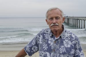 Prof Bill Fenical standing on the beach in front of Scripps Pier