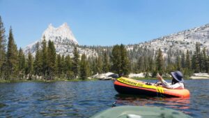 A scientist in a small orange raft paddles out in a freshwater lake.